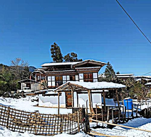 a house with snow on the ground in front of it at Nobgang B&B (Restaurant and Lodge) in Punākha