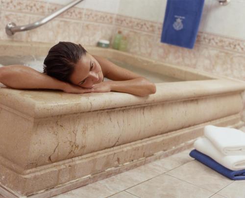 a woman is laying in a bath tub at Hotel Parque Balneario Termas Pallares in Alhama de Aragón