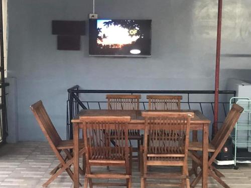 a wooden table with chairs and a television on a wall at A Unique and Cozy WholeHouse in Babak Samal Island in Babak