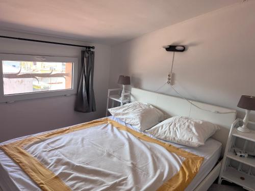 Schlafzimmer mit einem Bett mit weißer Bettwäsche und einem Fenster in der Unterkunft L’Amirall in Roses