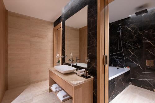 The Bentley Luxury Hotel & Suites في الدوحة: حمام مع حوض وحوض استحمام