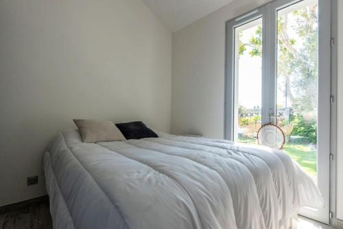 - une chambre blanche avec un grand lit et une fenêtre dans l'établissement Maison Tiki Village Aix centre, à Aix-en-Provence