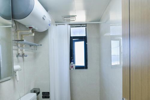 a bathroom with a toilet and a window at Sea View Apartment with Washer Dryer Projector Refrigerator and Kitchen Shantou South High-Speed Railway St ation in Shantou
