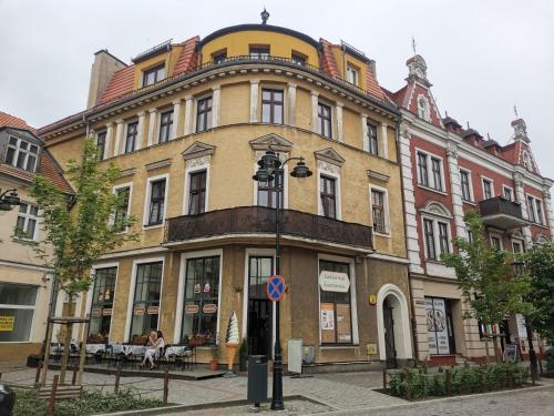 a large building with people sitting outside of it at Apartament na Rynku w Gnieźnie in Gniezno