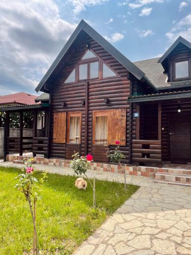a wooden house with a dog laying in the grass at Sky High Kolasin in Kolašin