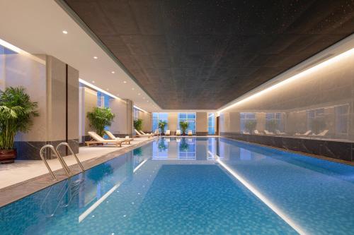 a swimming pool in a hotel with chairs and tables at Wanda Jin Jiamusi in Jiamusi