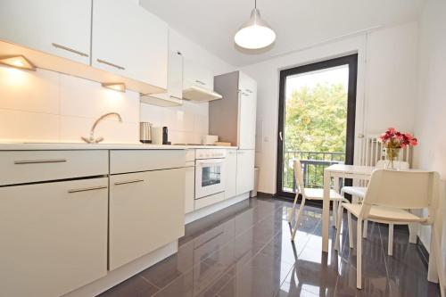 een keuken met witte kasten en een tafel met stoelen bij Air Apartments 1 in Bremen