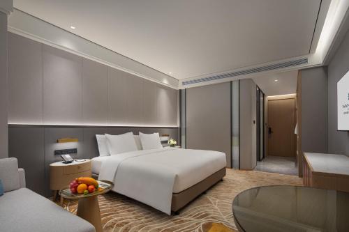 a bedroom with a large white bed and a living room at Wanda Jin Jiamusi in Jiamusi