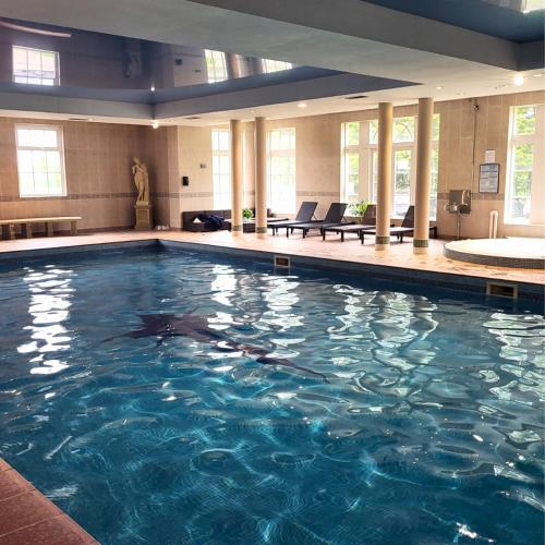 a large swimming pool with blue water in a building at Shaw Hill Hotel Golf And Country Club in Chorley