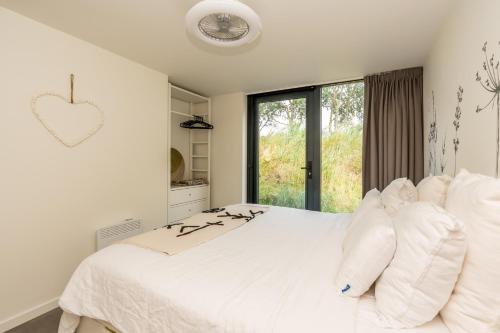 a white bedroom with a large bed with white pillows at Riethoek Westerschouwen in Burgh Haamstede