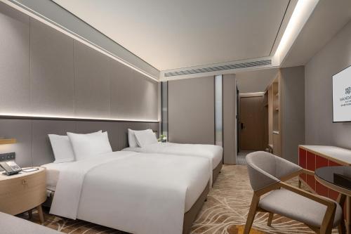 a hotel room with two beds and a desk at Wanda Jin Jiamusi in Jiamusi