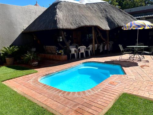 a swimming pool in front of a hut with a table and an umbrella at GUESTHOUSE SHALOM in Springs