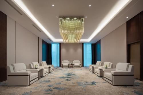 a waiting room with white chairs and a chandelier at Wanda Jin Jiamusi in Jiamusi