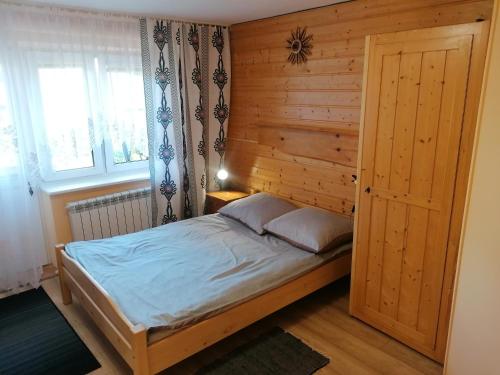 a bedroom with a bed with a wooden wall at Wypoczynek u Bożeny i Edka Tkaczyków in Grywałd