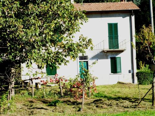 una casa blanca con persianas verdes y un árbol en IL FAGGIO ROSSO en Missaglia