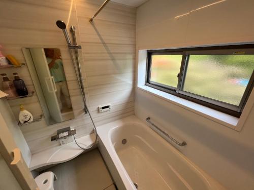 a bathroom with a tub and a window at Den House in Oshima