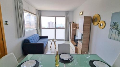 ein Wohnzimmer mit einem Tisch und einem blauen Sofa in der Unterkunft Moderno apartamento con terraza privada y vistas in Benidorm
