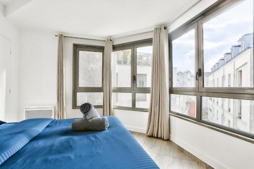 um urso de peluche sentado numa cama num quarto com janelas em Appartement Quartier Republique em Paris