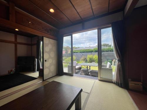 a living room with a table and a large window at Den House in Oshima