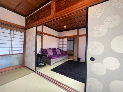 Den House في Oshima: غرفة معيشة مع أريكة أرجوانية في غرفة