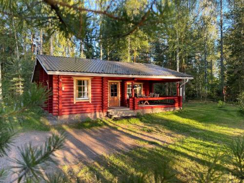 a small red cabin in the middle of a forest at Säilöksen Lomahuvilat in Luhanka
