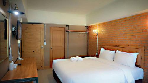 a bedroom with a white bed and a brick wall at The Old Inn in Udon Thani