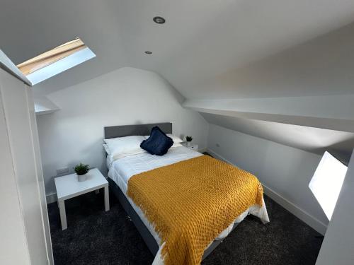 a bedroom with a bed with a yellow blanket at THE GLASS HOUGHTON APARTMENTS in Castleford