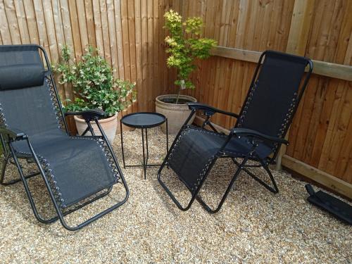 three black chairs and a table in front of a fence at The Old Garage in West Itchenor