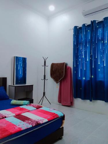 a bedroom with a bed and blue and red curtains at CozyL Homestay in 3 minutes drive to Redang Jetty in Kampong Ru Sepuloh