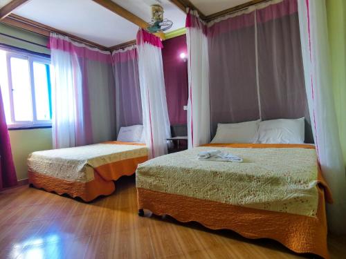 duas camas num quarto com cortinas cor-de-rosa em Hotel Basilea Mtwapa em Mtwapa