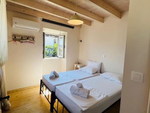 een slaapkamer met 2 bedden en handdoeken bij Traditional Detached Corfu House, 50m to village square in Liapades