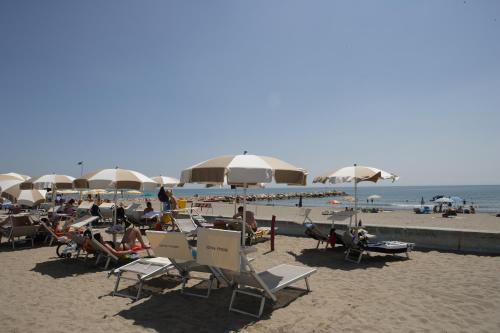 a beach with people sitting in chairs and umbrellas at Eraclea Palace Hotel 4 stelle S in Eraclea Mare