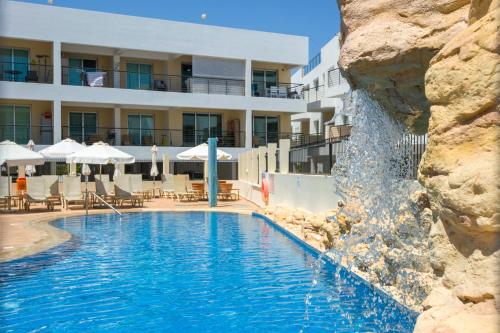 a swimming pool with a waterfall in front of a hotel at Sea View APT*Spacious balcony*200m to the Beach in Paralimni