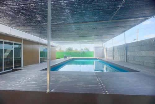 an empty swimming pool in a building with a ceiling at Bangkok Pool Villa Suvarnabhumi in Ban Hua Takhe