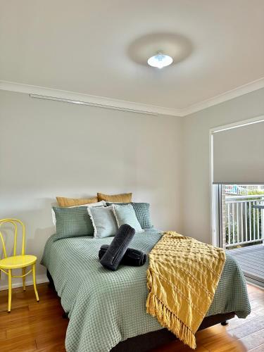 a bedroom with a green bed with a yellow chair at Hillston House in Kiama
