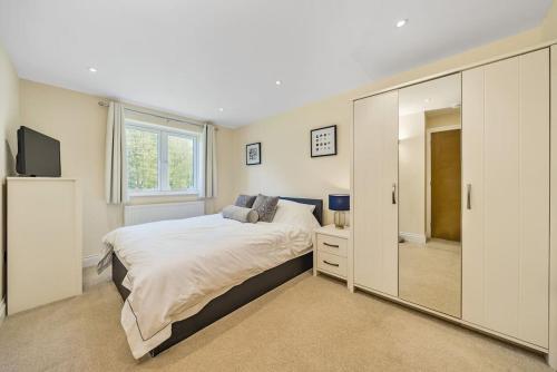 a bedroom with a large bed and a mirror at Country cottage & Tennis court in Warnham