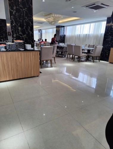 a lobby with a restaurant with tables and chairs at Grand Palace Hotel Lusaka in Lusaka