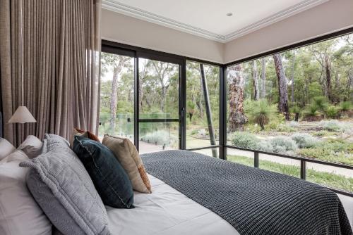 a bedroom with a bed and a large window at Songbird I Private Properties in Yallingup