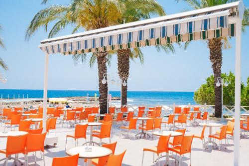 a beach with orange chairs and tables and palm trees at Oz Hotels Incekum Beach in Alanya
