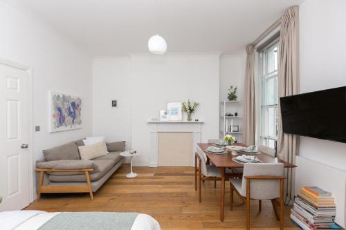 a living room with a table and a couch at Light filled studio with view of Regents Park in London