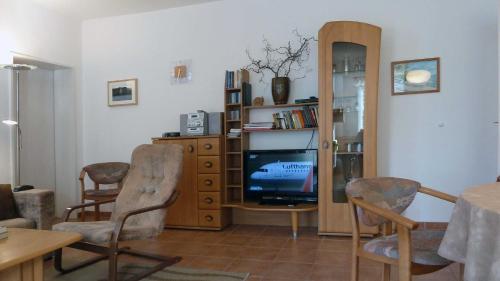 ein Wohnzimmer mit einem TV, einem Tisch und Stühlen in der Unterkunft Haus Holstein Meinke WE 13 W-LAN in Ostseebad Sellin