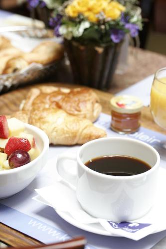 uma mesa com uma chávena de café e uma taça de fruta em Kyriad Hotel XIII Italie Gobelins em Paris