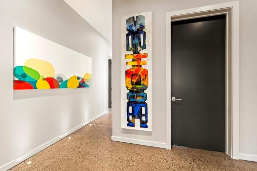 a hallway with two paintings on the wall and a black door at Hapuna Modern House at Mauna Kea in Hapuna Beach
