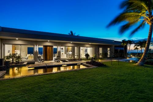a large house with a swimming pool and a palm tree at Hapuna Modern House at Mauna Kea in Hapuna Beach