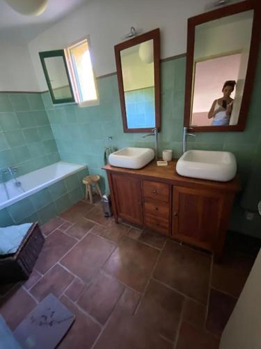 ein Badezimmer mit zwei Waschbecken, einer Badewanne und einem Spiegel in der Unterkunft Pavillon dans un écrin de verdure avec piscine in Lodève