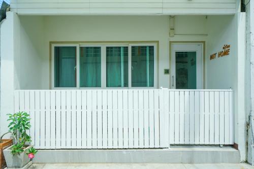 a white fence in front of a white house at Nut Home Hostel in Ban Ko