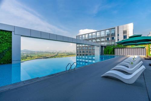 a swimming pool with chairs and an umbrella on a building at EVEN Hotels Shenzhen Guangming Cloud Park, an IHG Hotel in Shenzhen