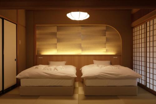 two twin beds in a room with a window at Oku Yugawara SANSUIROU in Yugawara