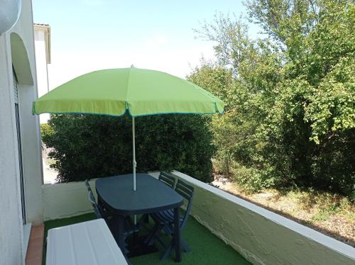 een tafel met een groene parasol op een balkon bij LE SOLEIL DU LUBERON - T2 avec Terrasse, Parking et Clim in LʼIsle-sur-la-Sorgue