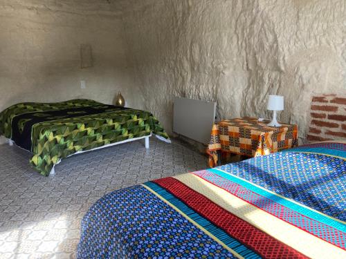 a bedroom with two beds and a table with a lamp at Nuit insolite dans une troglodyte ! in Nazelles